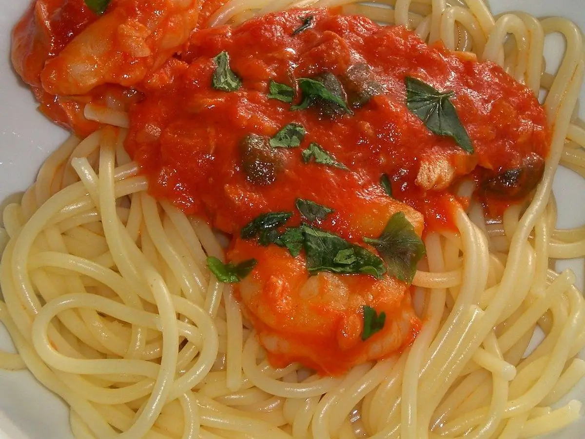 Pasta con salsa de tomate espesa y hojas de perejil en un plato