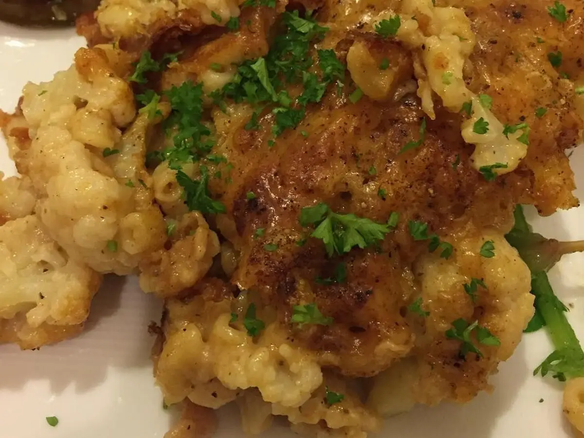 Macarrones gratinados con coliflor y perejil picado en un plato blanco