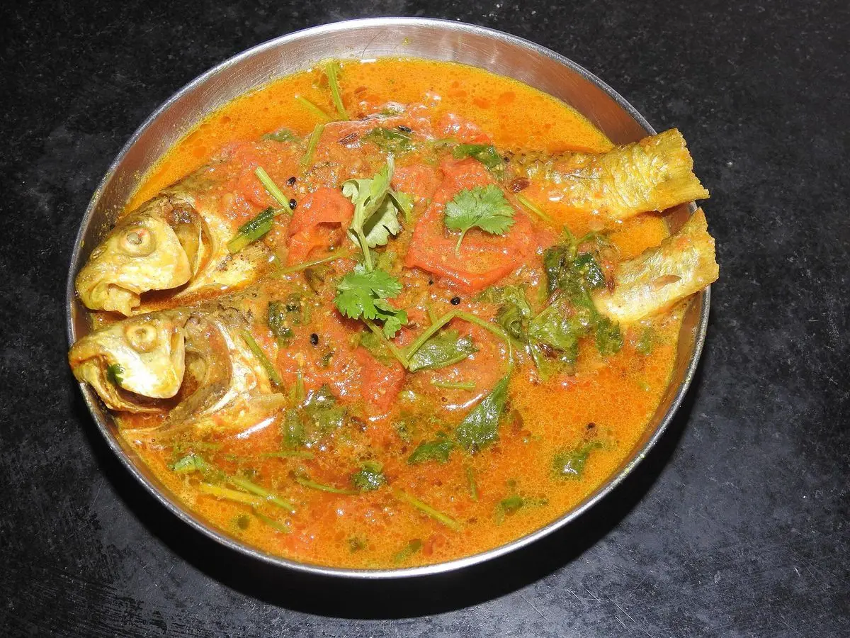 Pescado entero en caldo rojo de tomate con cilantro fresco servido en un plato metálico