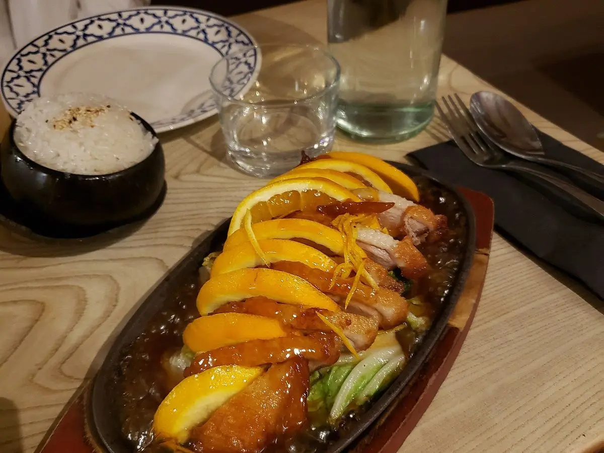 Magret de pato laminado con rodajas de naranja sobre una plancha caliente