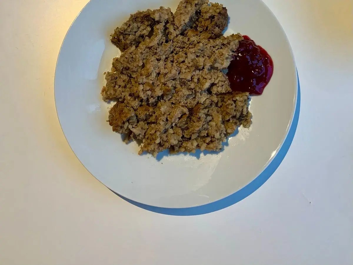 Ración de pastel de hígado y arroz al horno con mermelada de arándanos rojos en un plato blanco
