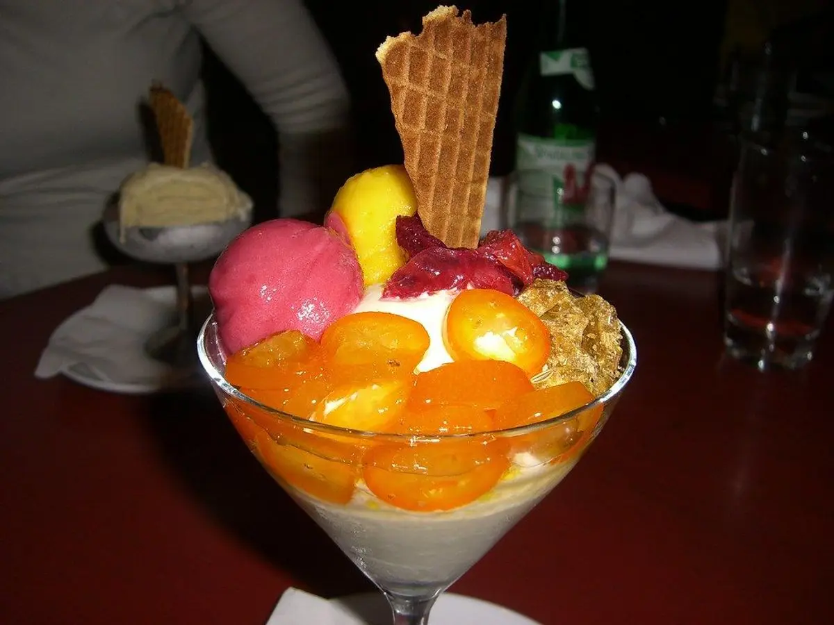 Copa de postre con gajos de mandarina, sorbetes de colores, nata y barquillo