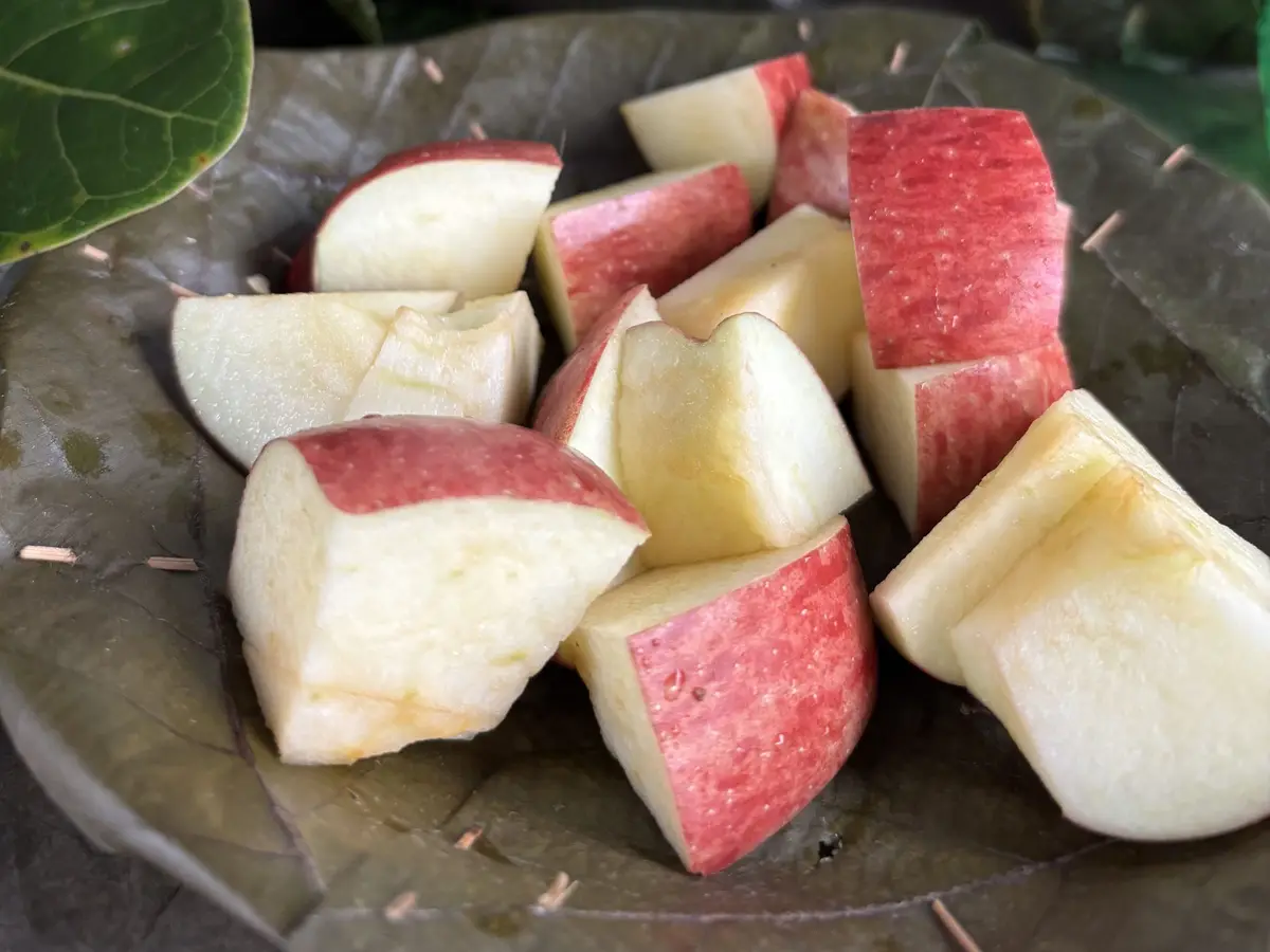 Gajos de manzana roja sobre un plato de hojas