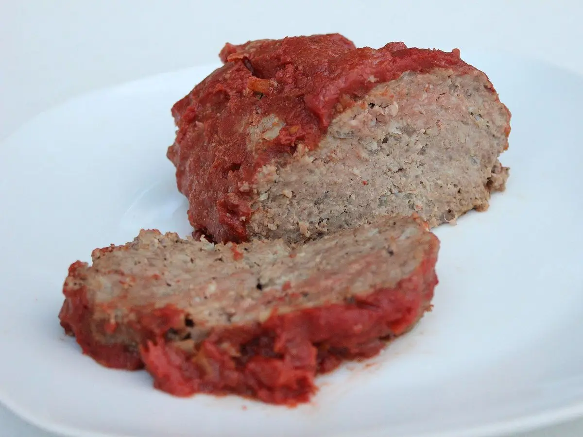 Rodajas de pastel de carne glaseado con salsa roja sobre un plato blanco