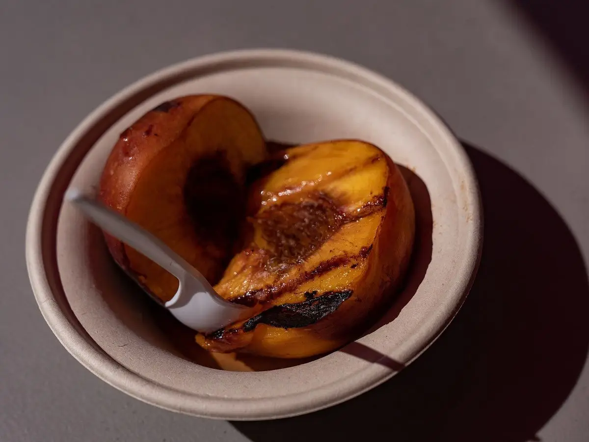 Melocotones asados caramelizados en un cuenco de barro con una cuchara