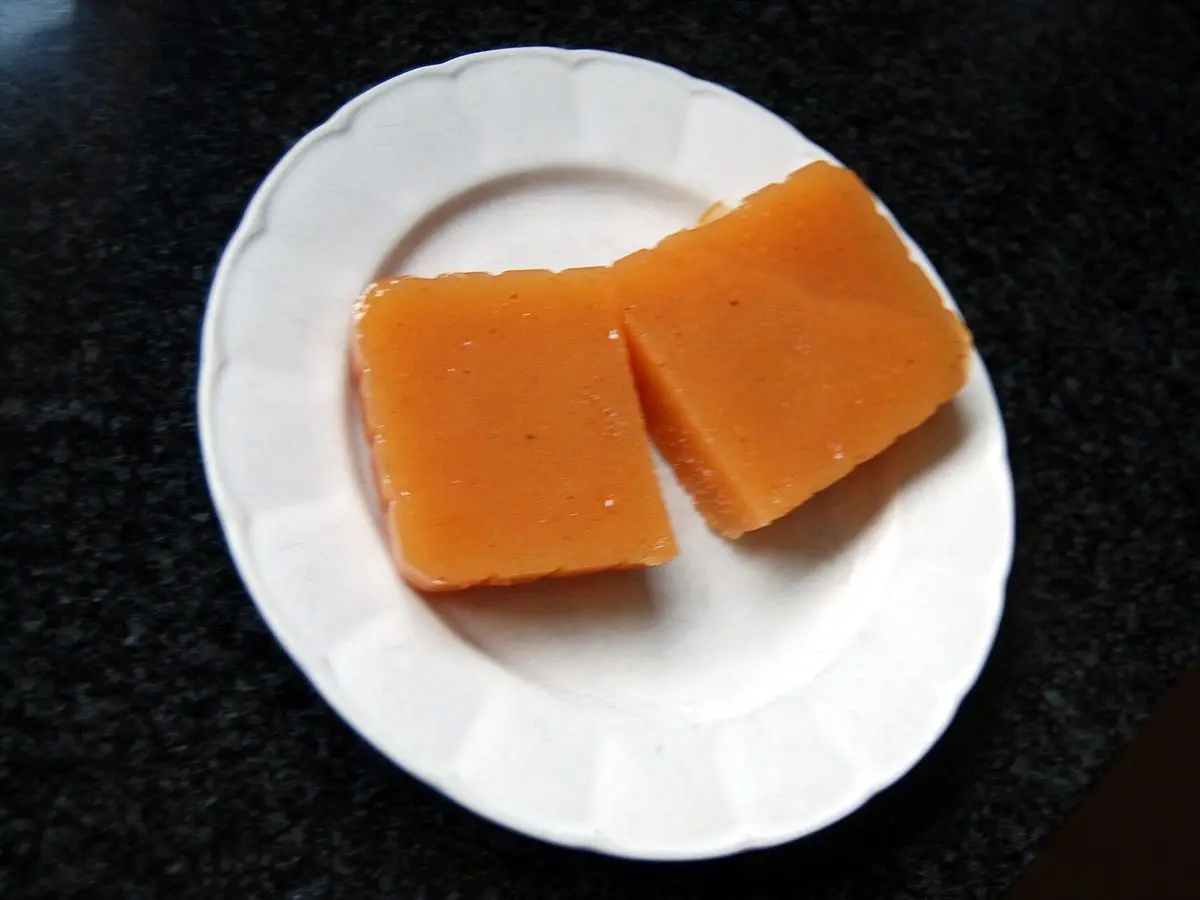 Dos porciones de dulce de membrillo anaranjado sobre un plato blanco