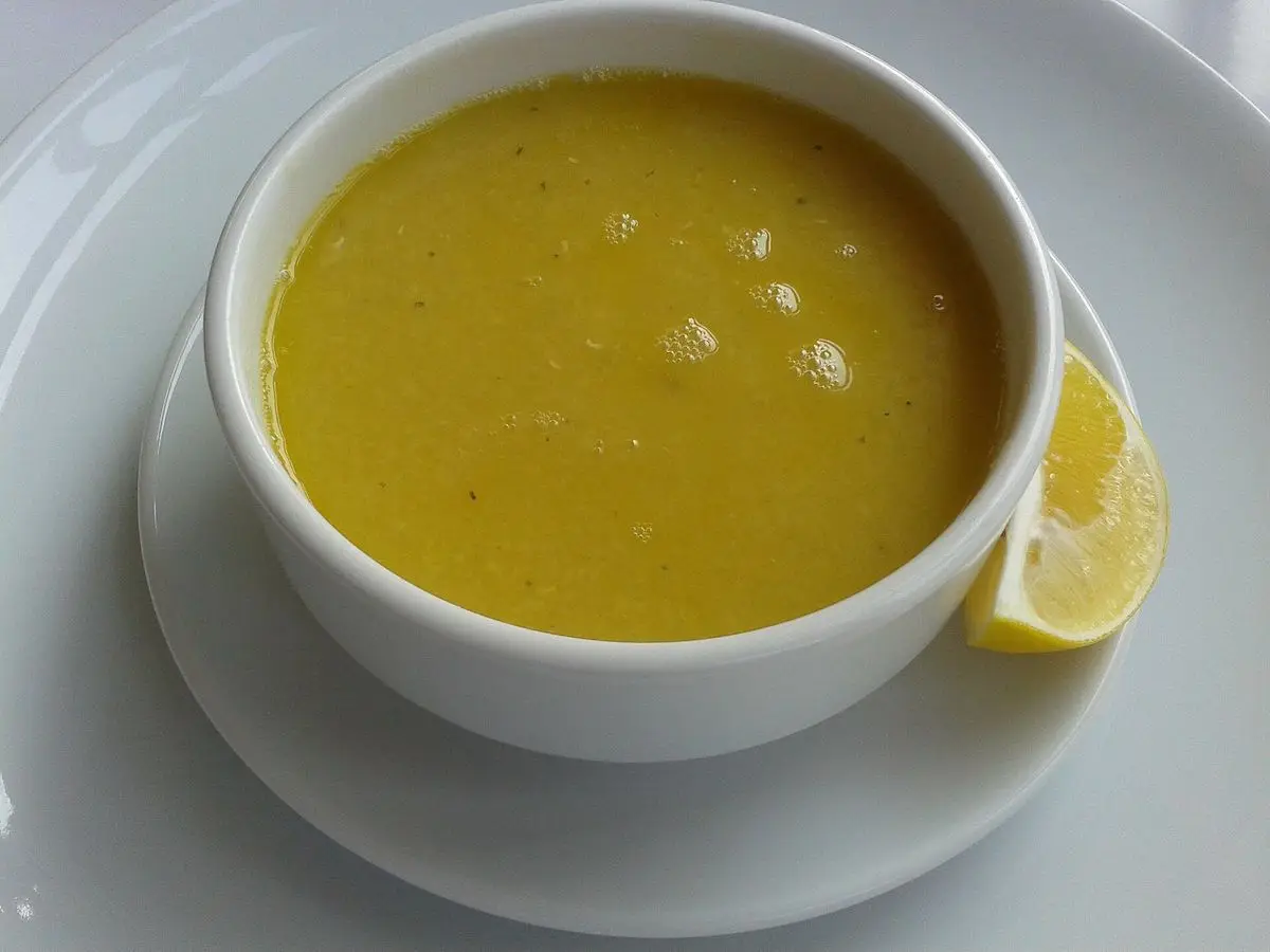 Cuenco blanco de crema de lentejas rojas anaranjada con una rodaja de limón al lado
