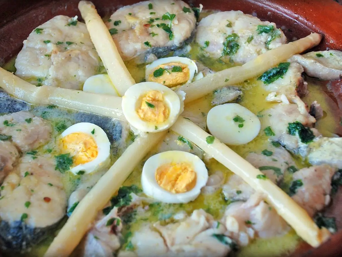 Merluza en salsa verde con espárragos blancos y huevo cocido en una cazuela de barro
