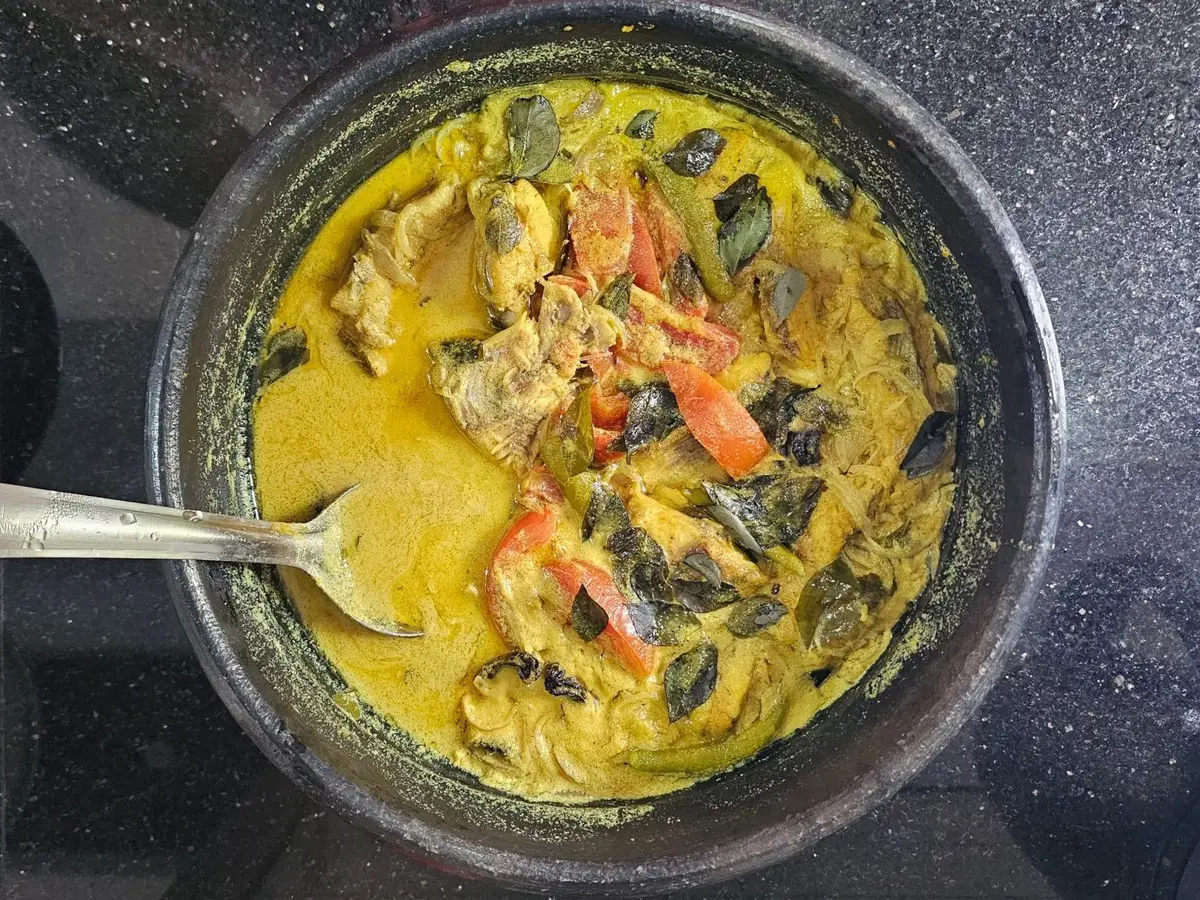 Guiso de pescado con tomate y leche de coco en una cazuela negra