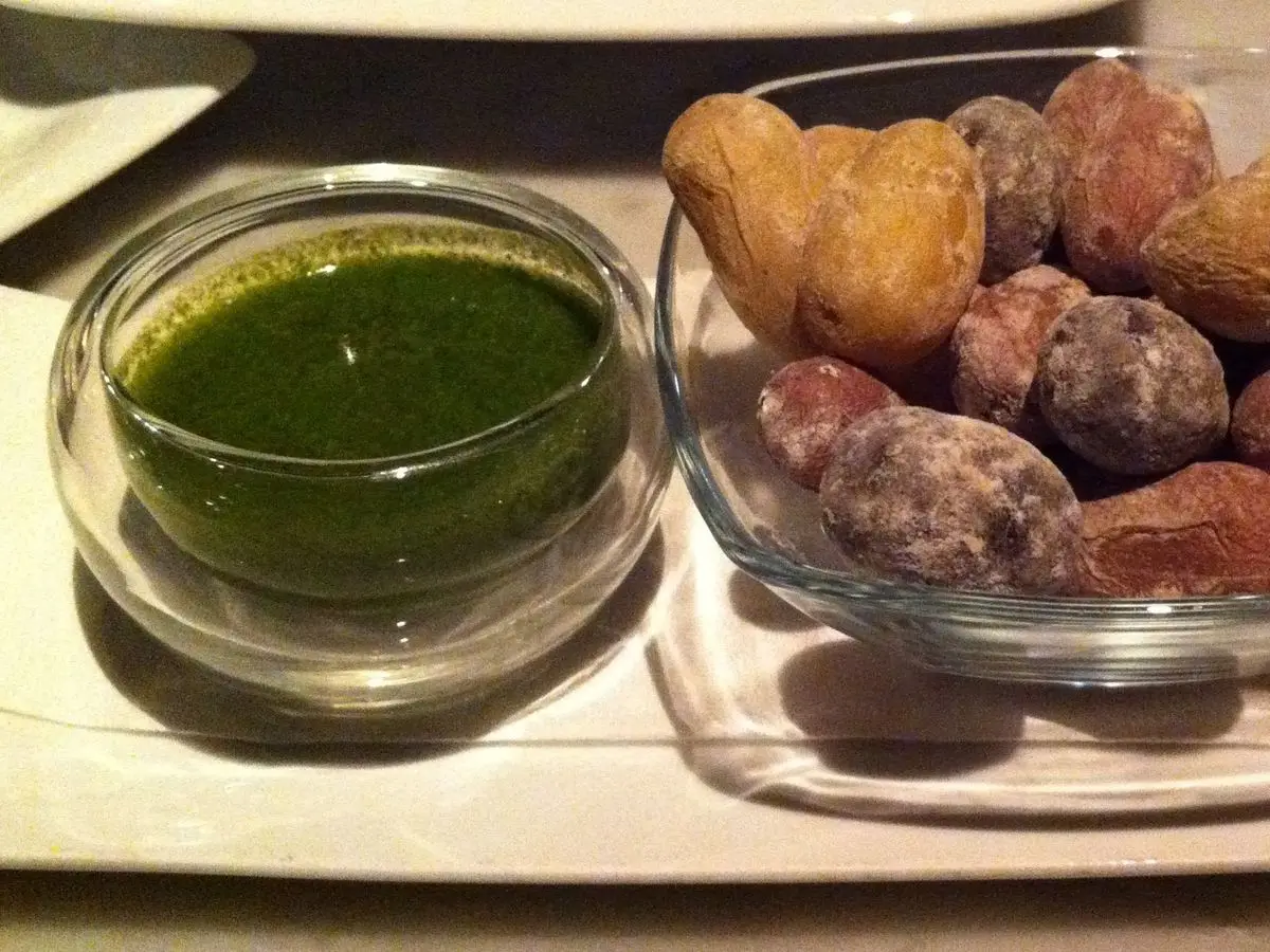 Papas arrugadas en una fuente de cristal con salsa mojo verde al lado