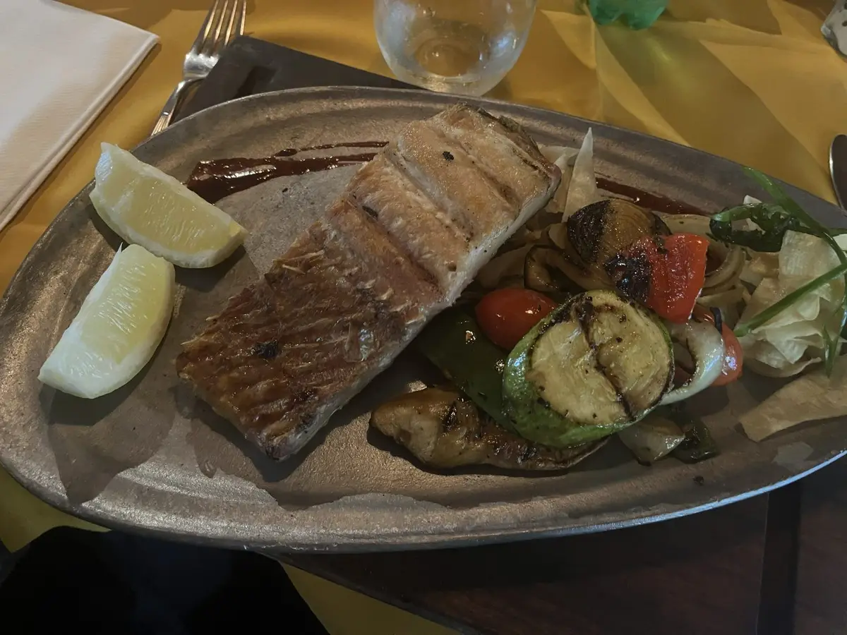 Pescado a la parrilla con limón y verduras asadas en una fuente