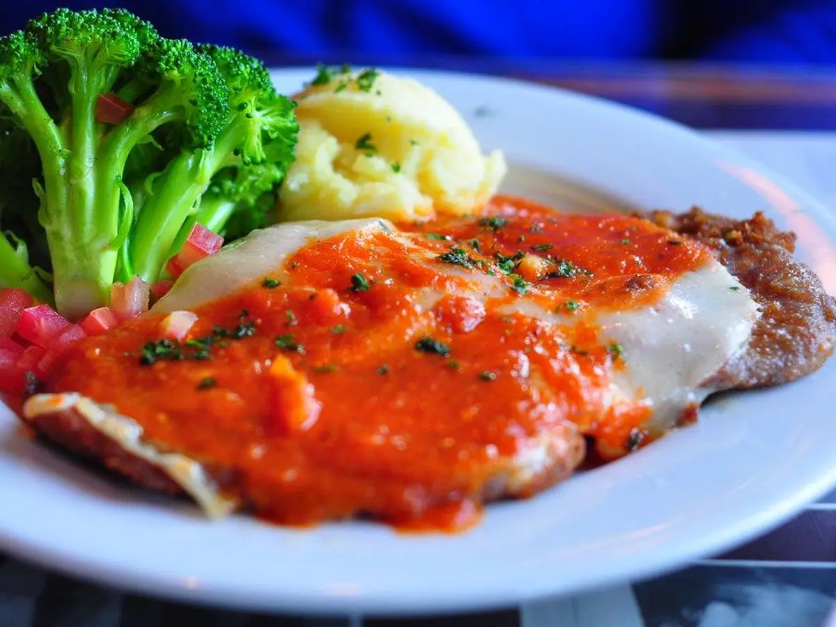 Filete de pescado con salsa de tomate, brócoli y patata en un plato blanco