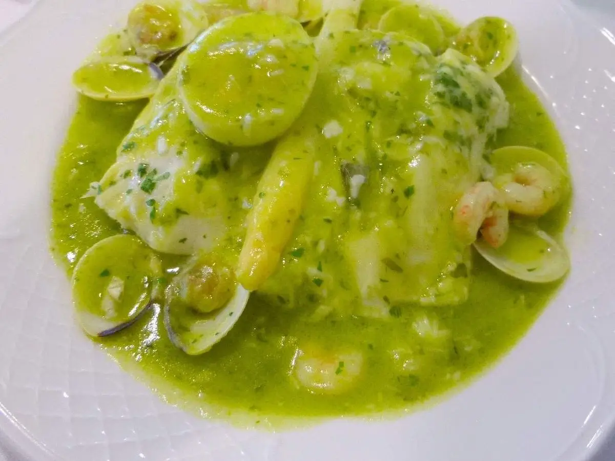 Plato blanco con merluza y almejas en salsa verde con perejil