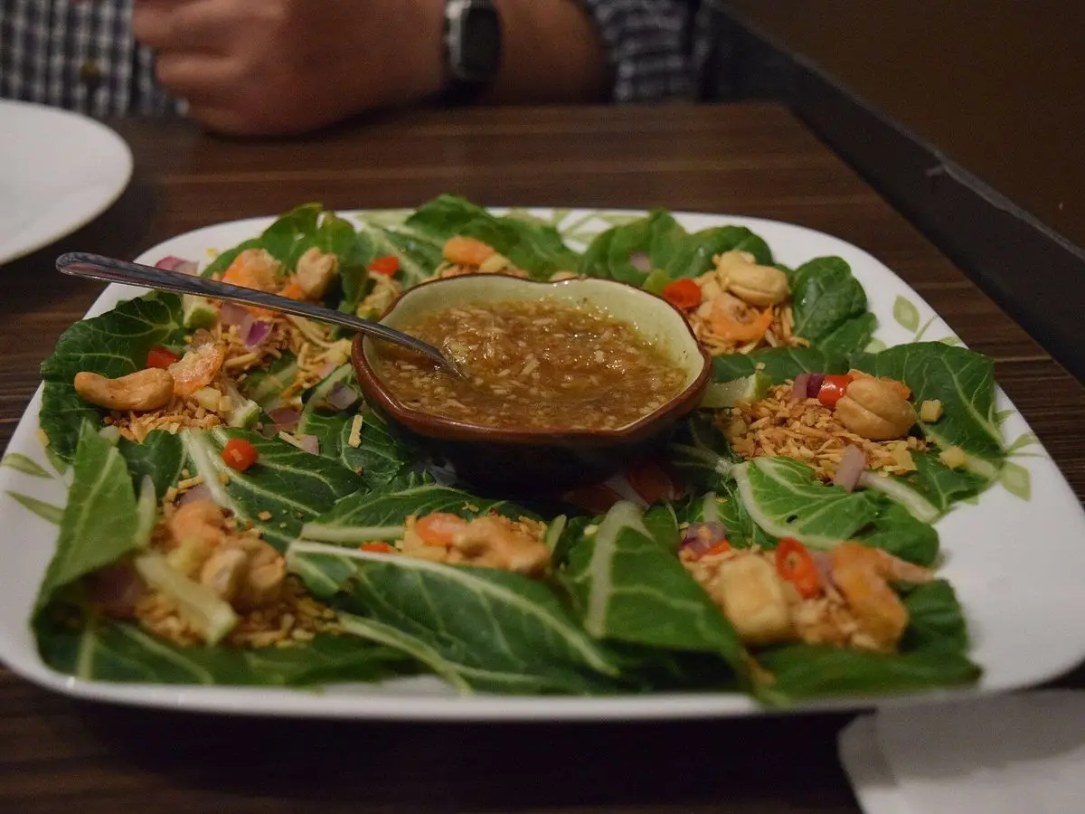 Bocados tailandeses miang kham en hojas verdes con relleno de gambas, cacahuete y salsa en un cuenco