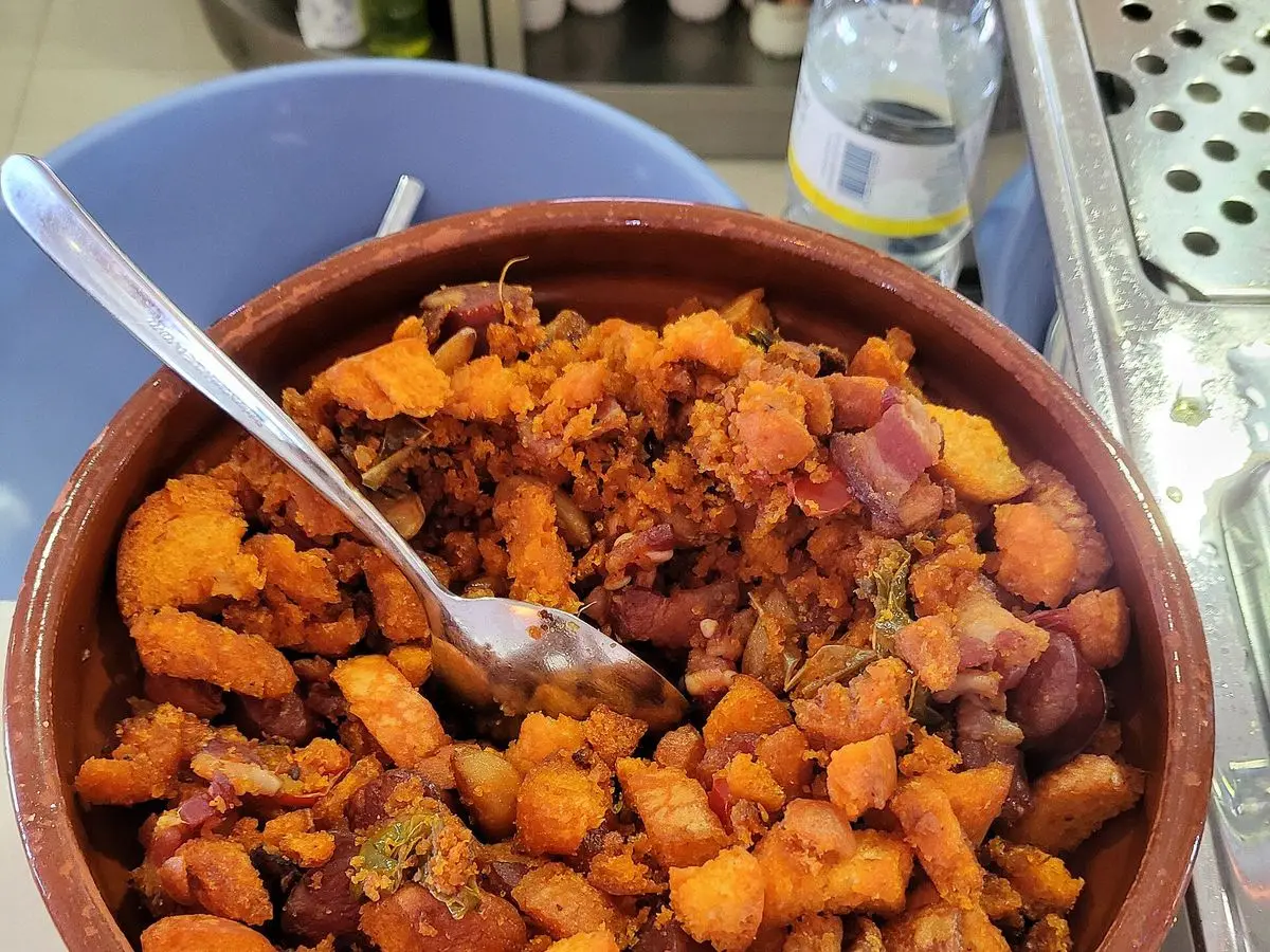 Cazuela de barro con migas de pan doradas y trozos de carne