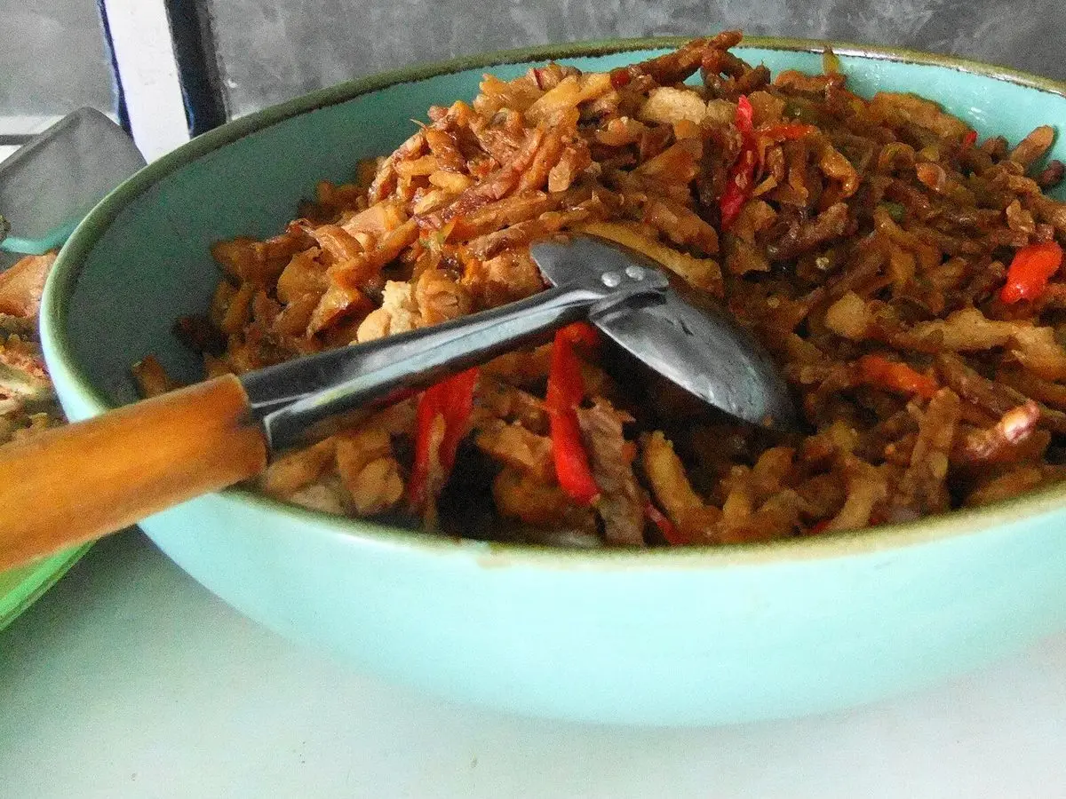 Cuenco turquesa con tempeh desmenuzado salteado con tiras de chile rojo y cuchara