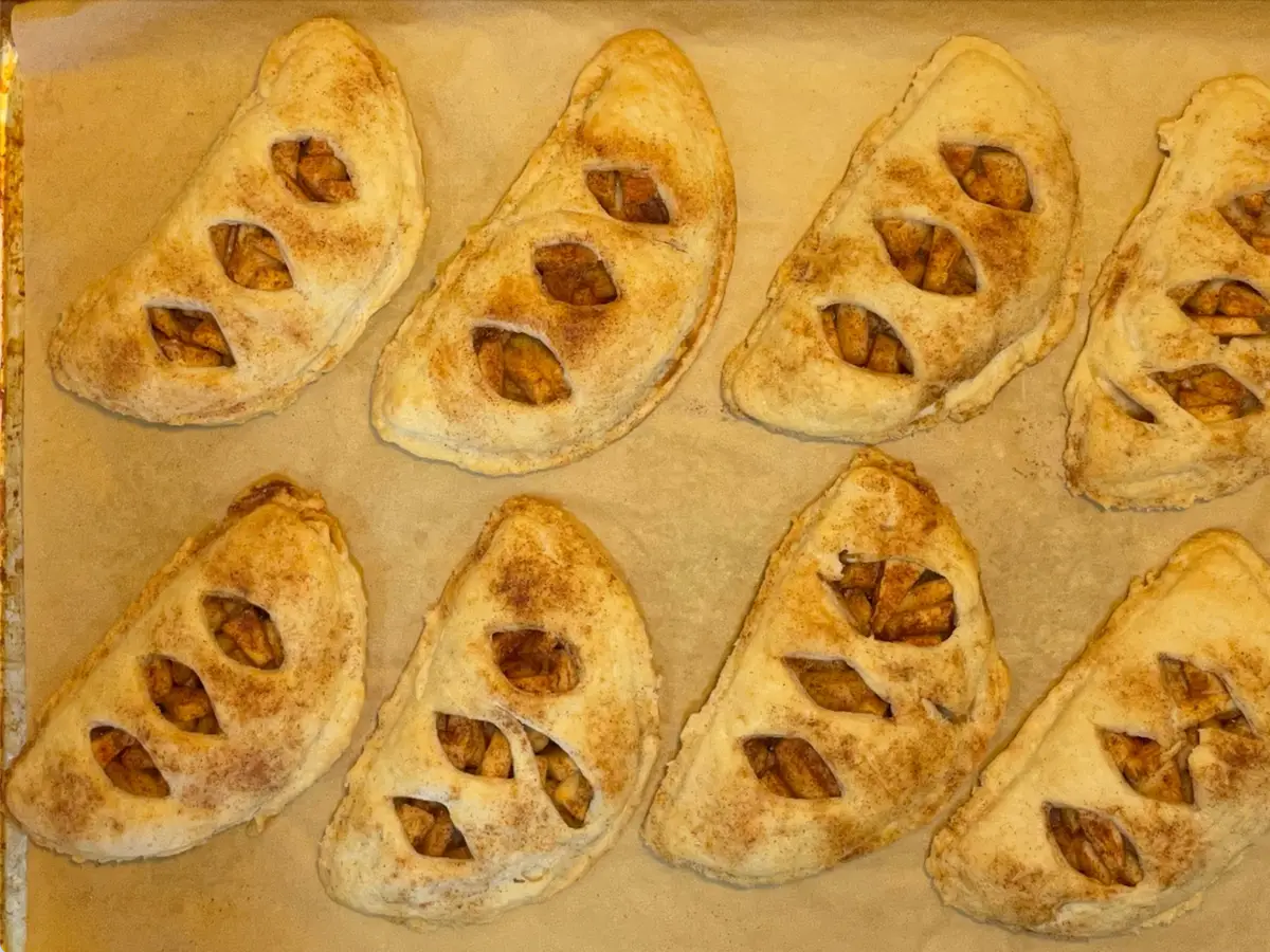 Empanadillas pequeñas horneadas y doradas con cortes decorativos sobre una bandeja
