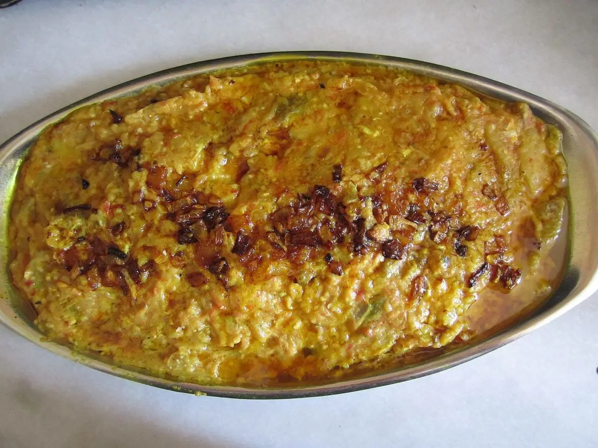 Fuente ovalada de berenjena ahumada machacada con tomate y huevo, dorada en la superficie
