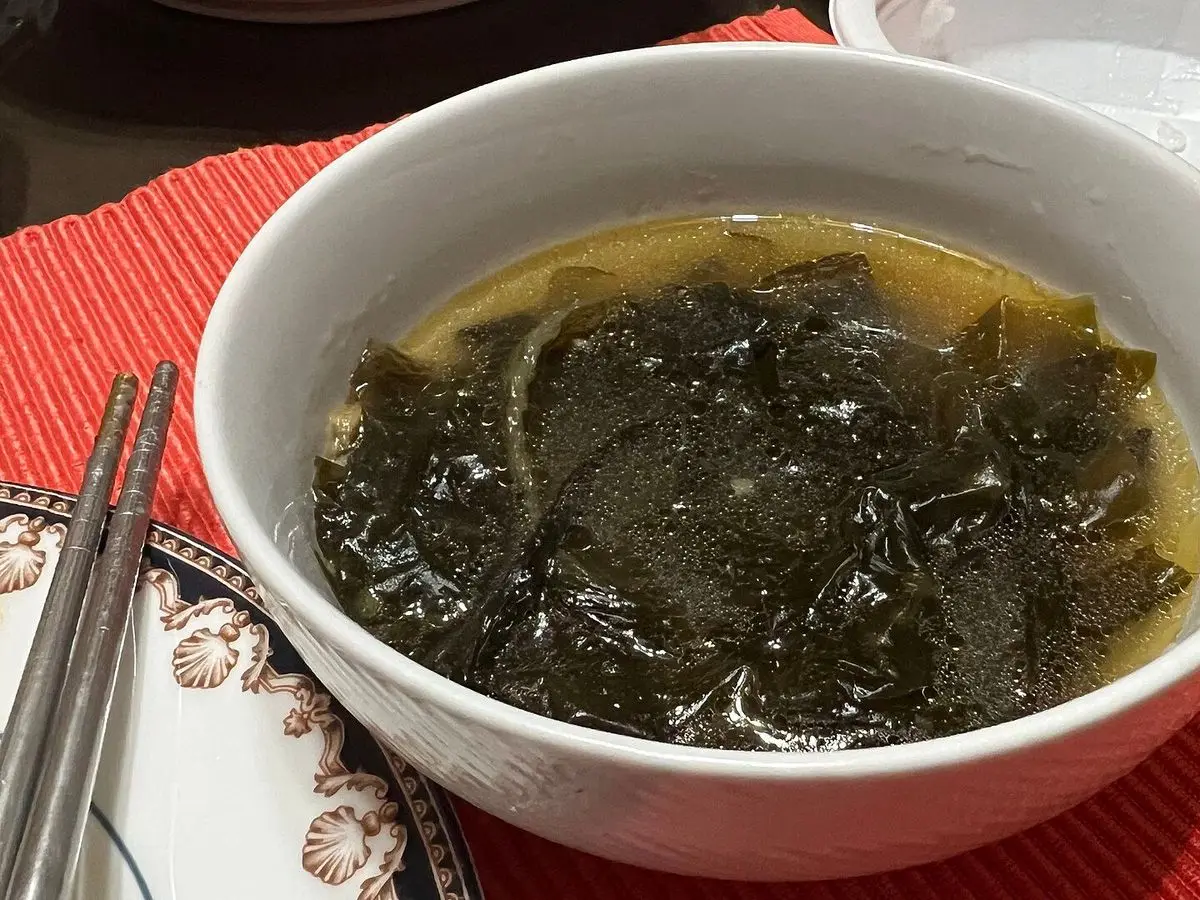 Cuenco blanco de sopa coreana de algas wakame sobre un mantel rojo
