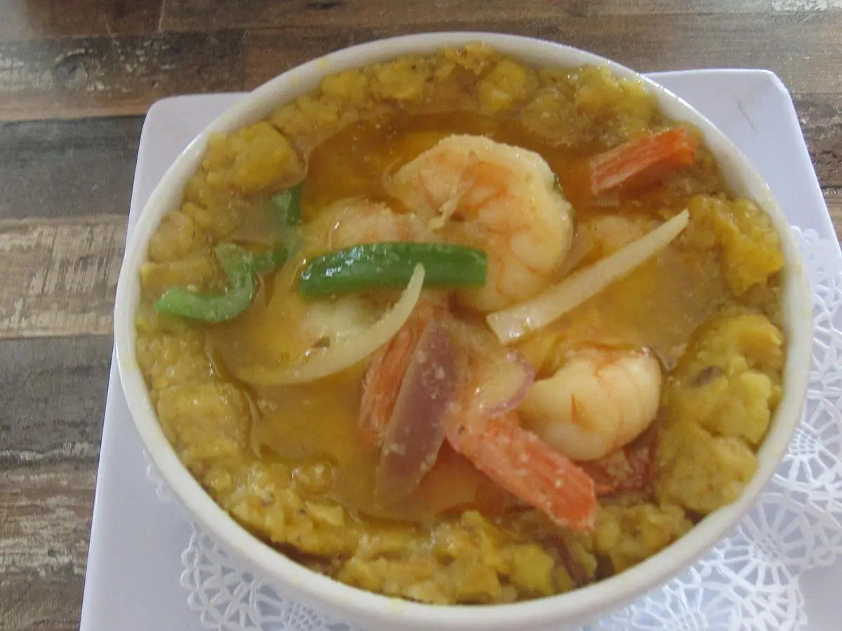 Cuenco de mofongo de plátano con gambas, pimiento verde y zanahoria en salsa criolla