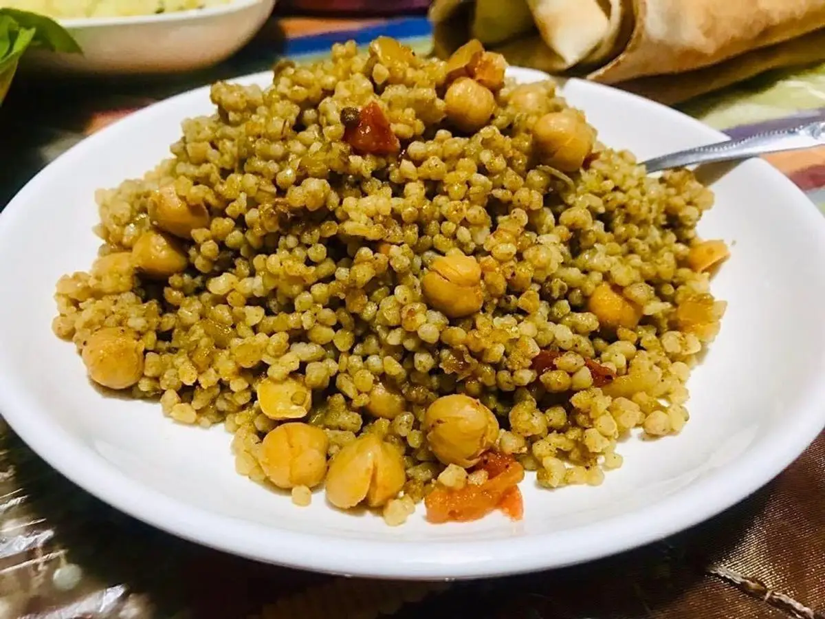 Plato blanco de cuscús perla de granos grandes con garbanzos y verduras en un guiso