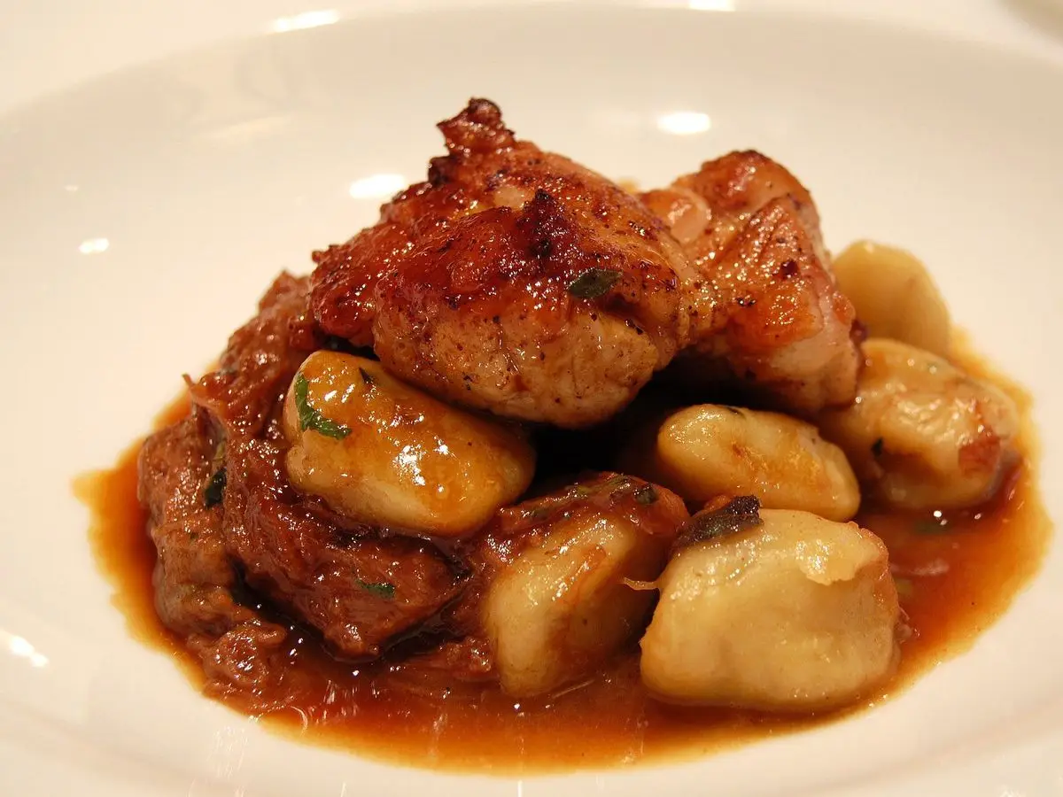 Mollejas doradas guisadas con ñoquis en salsa de carne sobre un plato blanco