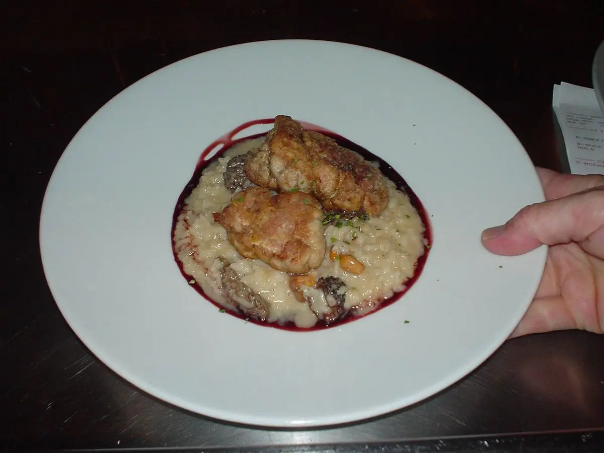 Mollejas doradas sobre una base cremosa con salsa morada en un plato blanco