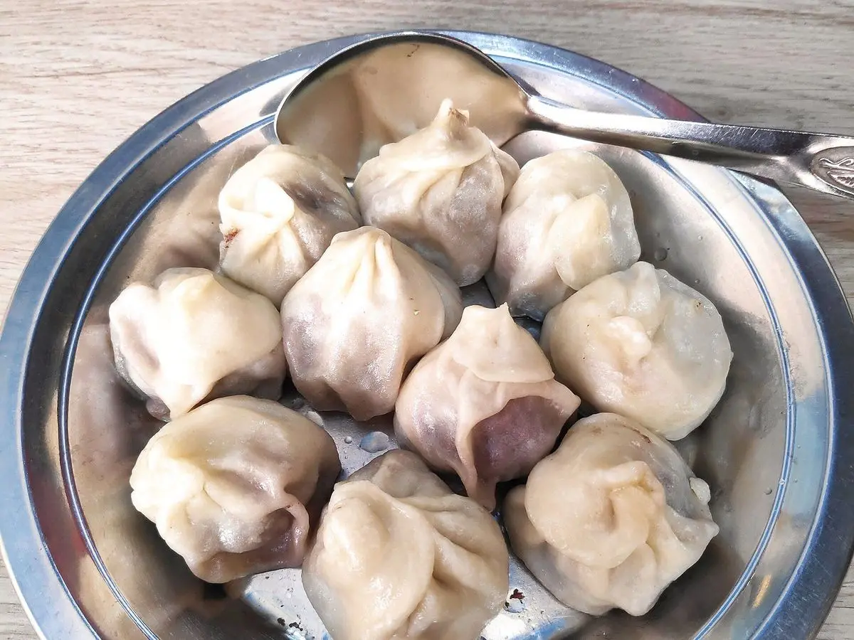 Momos nepalíes al vapor con pliegues, servidos en una bandeja metálica
