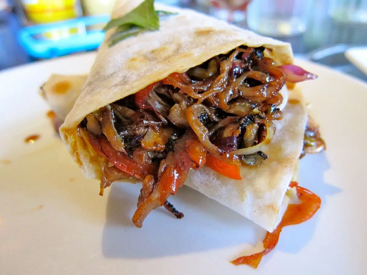 Burrito de moo shu con tortilla de trigo rellena de cerdo, col y zanahoria en un plato blanco