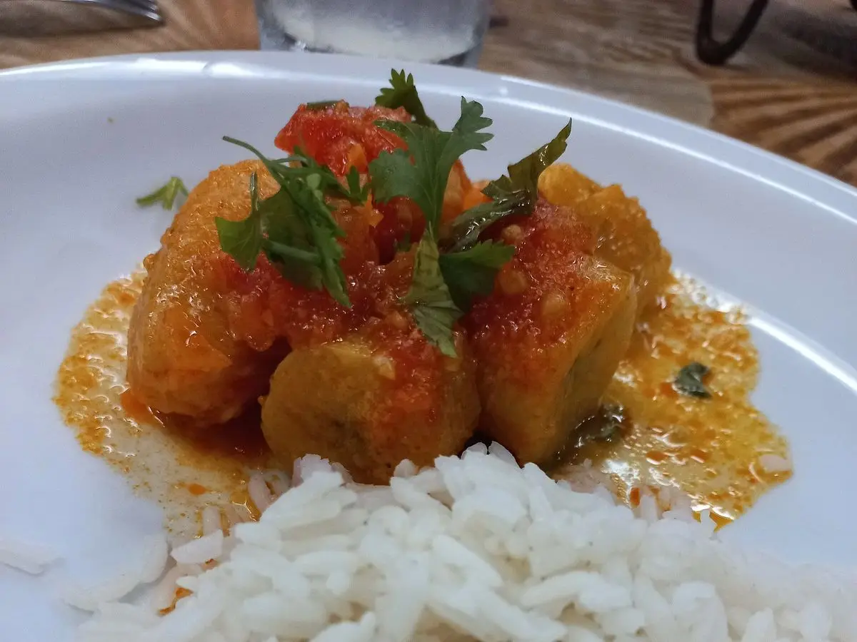 Moqueca de pescado en salsa anaranjada con cilantro servida con arroz blanco en un plato