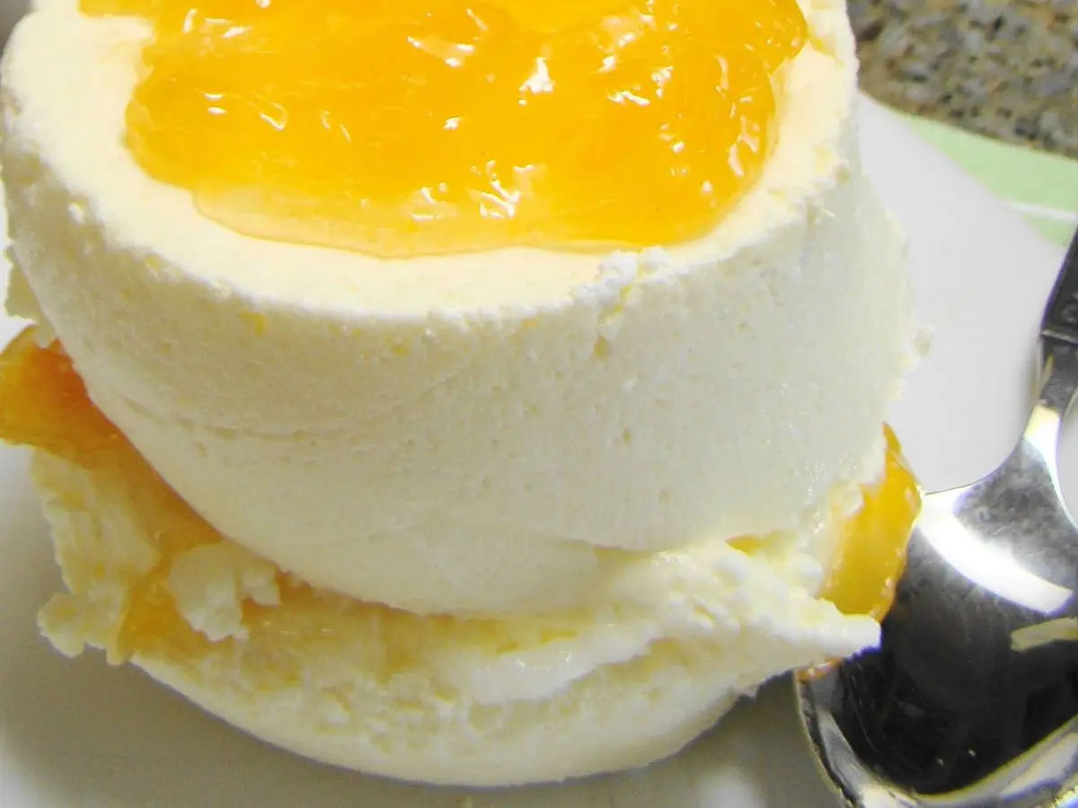 Postre cremoso de queso con cobertura de gelatina de fruta amarilla sobre un plato