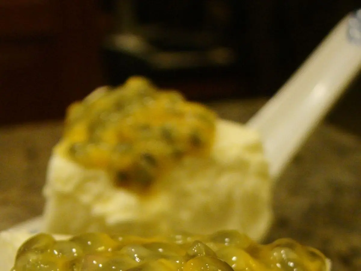 Porción de postre cremoso de queso blanco con maracuyá por encima, vista de cerca