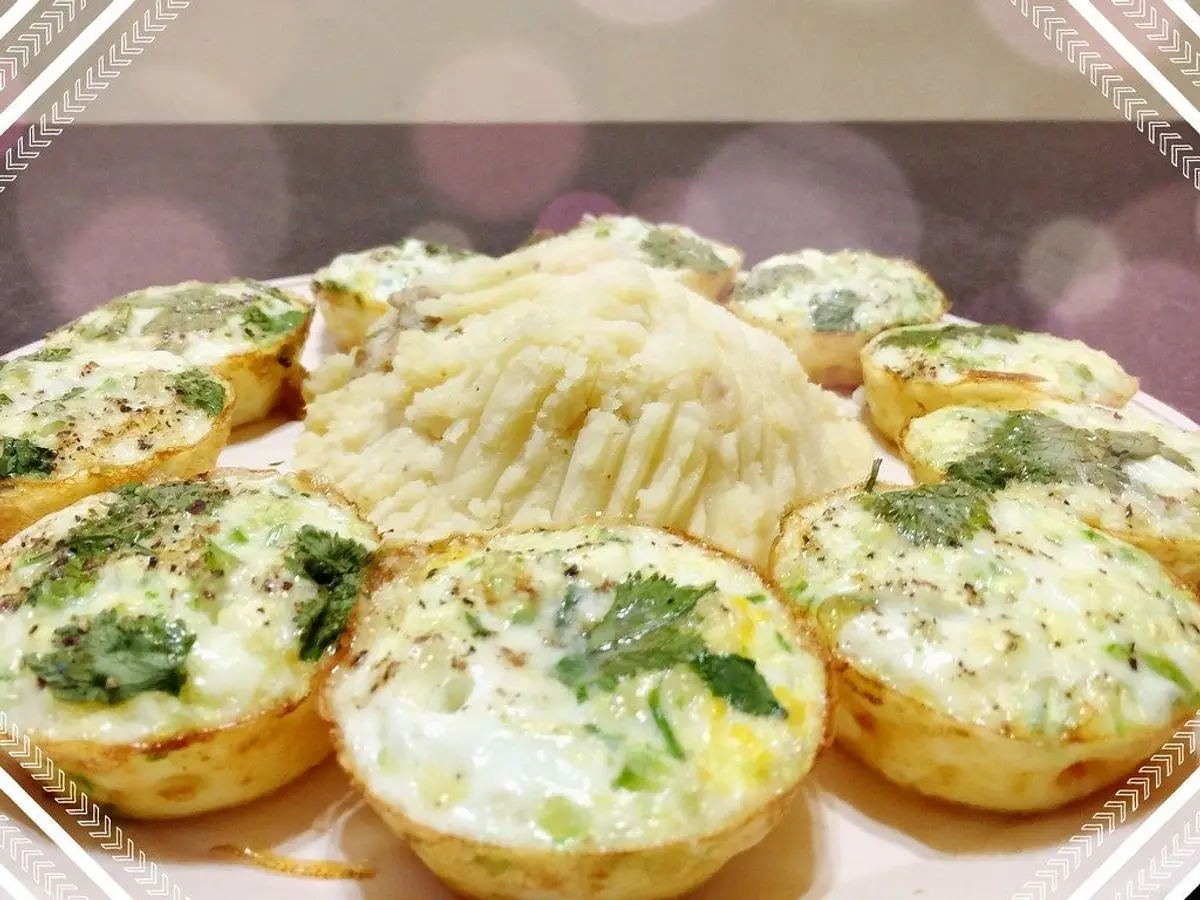 Bandeja de muffins de huevo cuajados con hierbas verdes por encima en moldes dorados