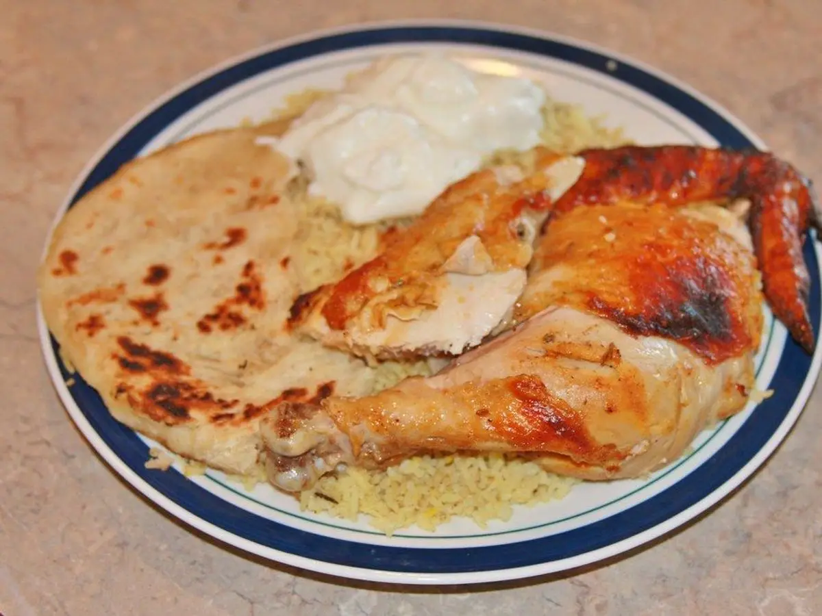 Plato con muslos de pollo asados, yogur y pan plano sobre cuscús
