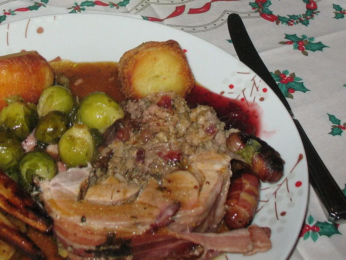 Muslo de pavo asado en rodajas con salsa, patatas asadas, coles de Bruselas y zanahoria