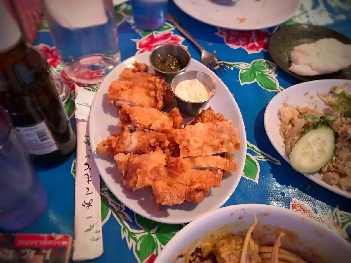 Muslos de pollo dorados y crujientes en un plato blanco sobre un mantel azul con flores