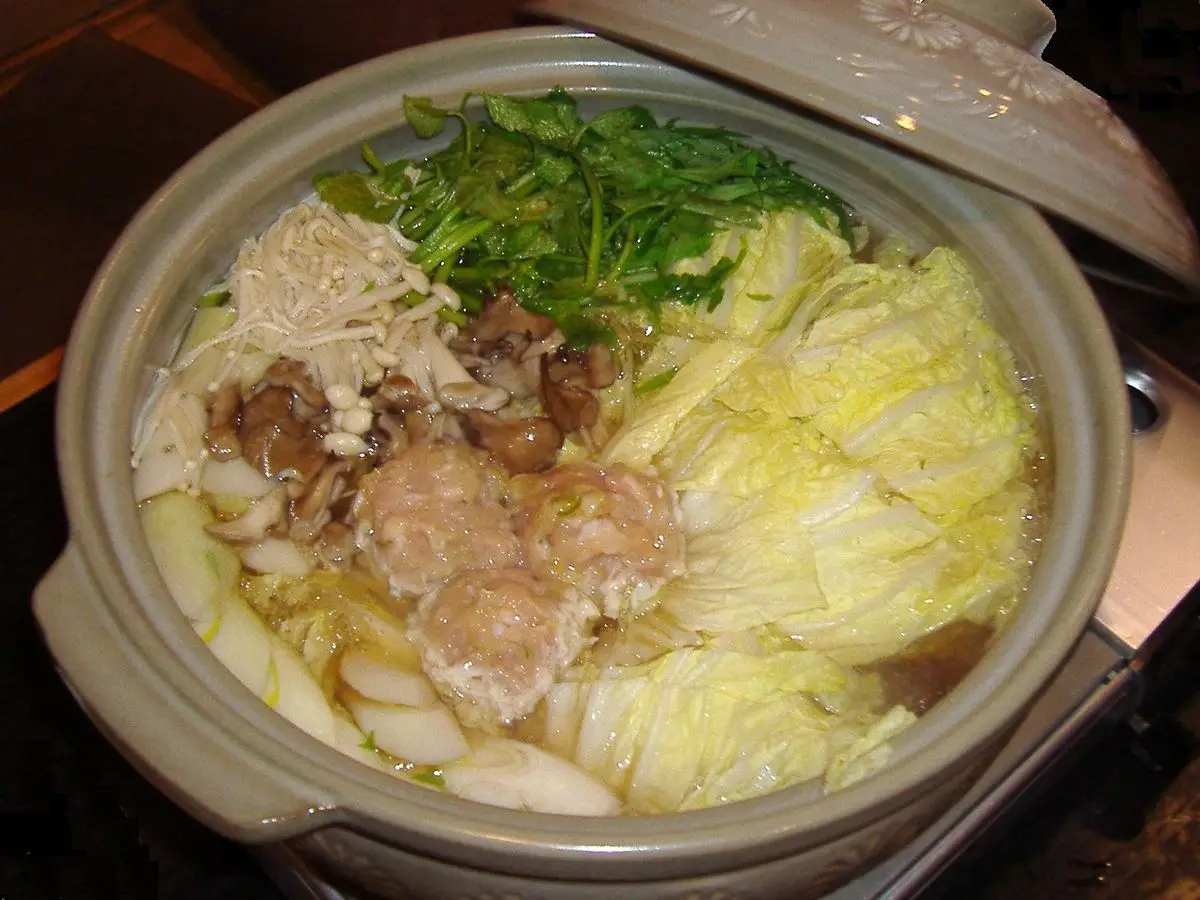 Olla de barro con nabe de col china, verduras de hoja y carne en caldo