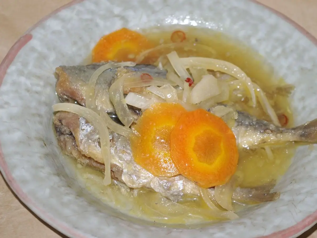 Pescados pequeños en escabeche con cebolla en juliana y rodajas de zanahoria en un plato hondo de cerámica