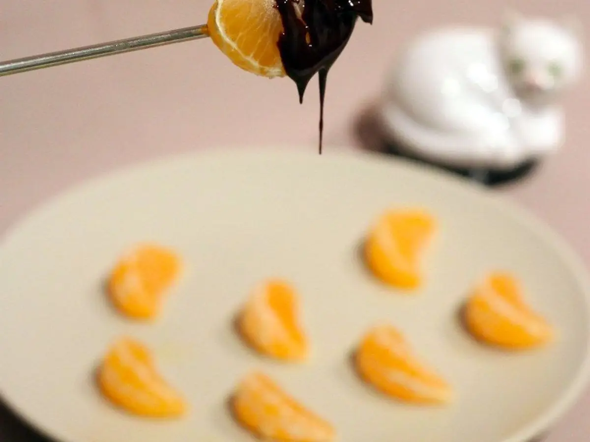 Gajo de mandarina bañado en chocolate negro sobre un plato con más gajos