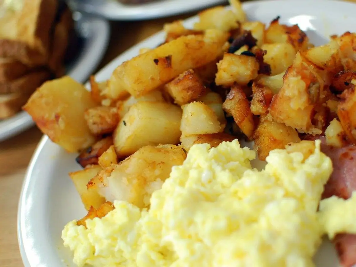 Patatas salteadas doradas con huevo revuelto en un plato blanco