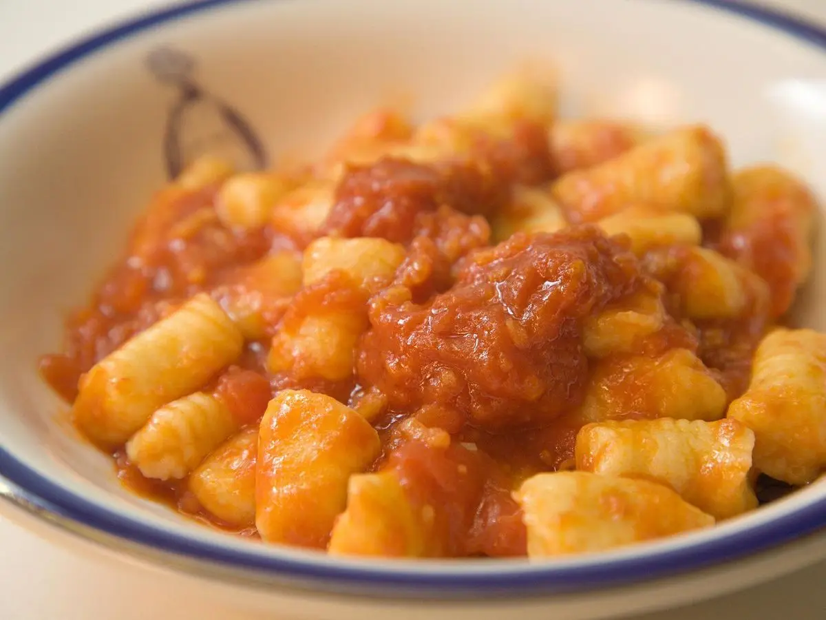 Ñoquis con salsa de tomate y carne en un cuenco blanco con borde azul