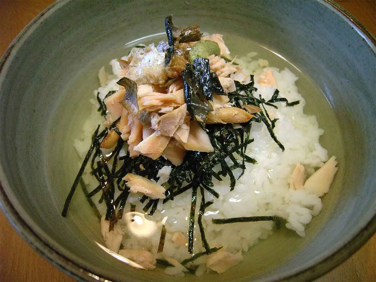 Cuenco de arroz con salmón desmenuzado, tiras de alga nori y té verde