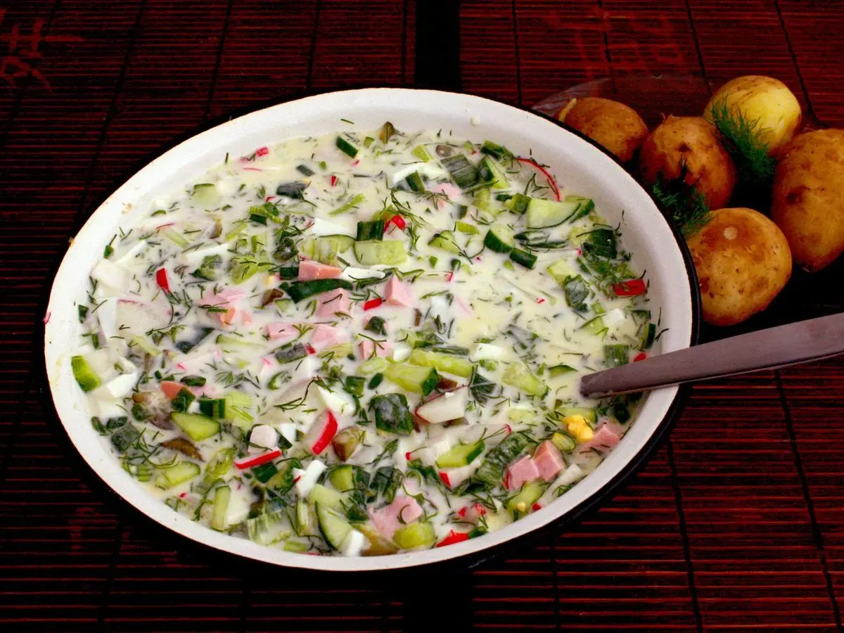 Cuenco grande de sopa fría de pepino, rabanitos, hierbas y embutido con patatas al lado