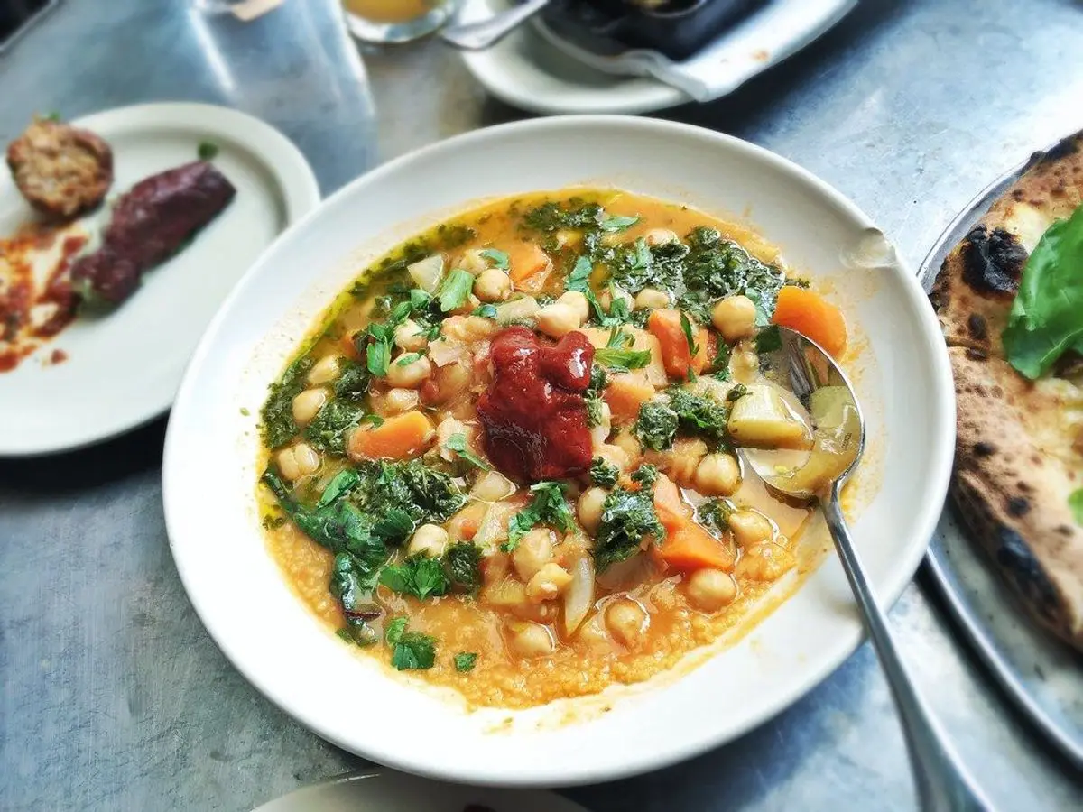 Plato hondo de garbanzos guisados con verduras y salsa de tomate