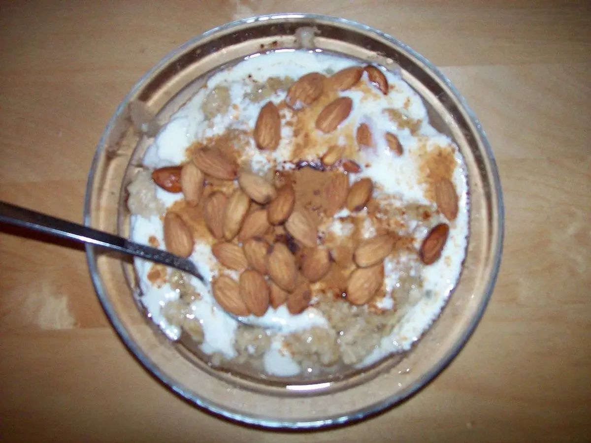 Cuenco de cristal con avena cremosa con yogur y frutos secos tostados por encima