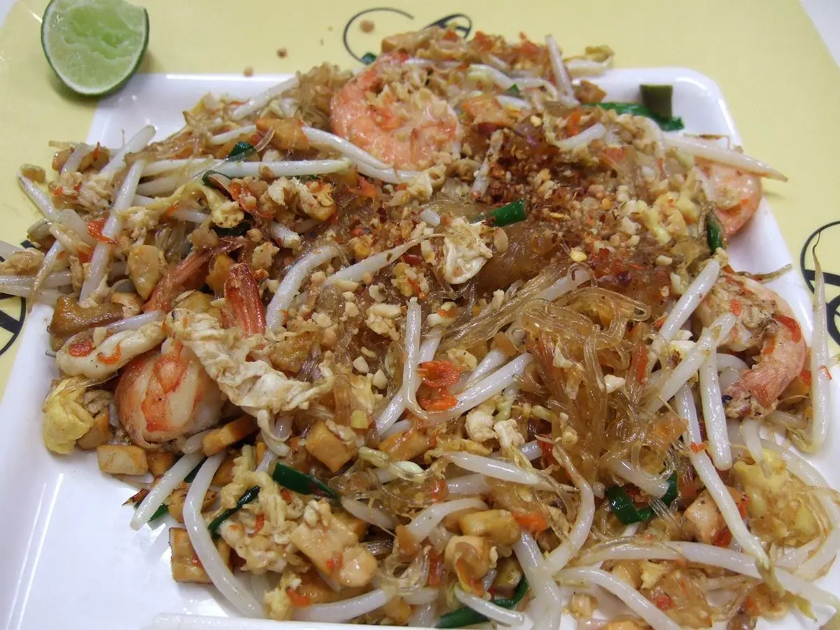 Fideos de soja transparentes salteados con gambas, brotes de soja y cacahuete picado con una rodaja de lima