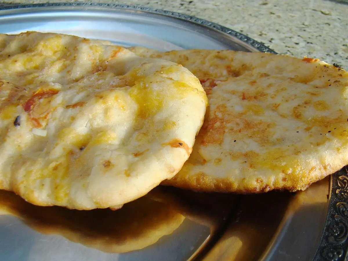 Dos panes planos dorados cocinados en sartén sobre una bandeja metálica