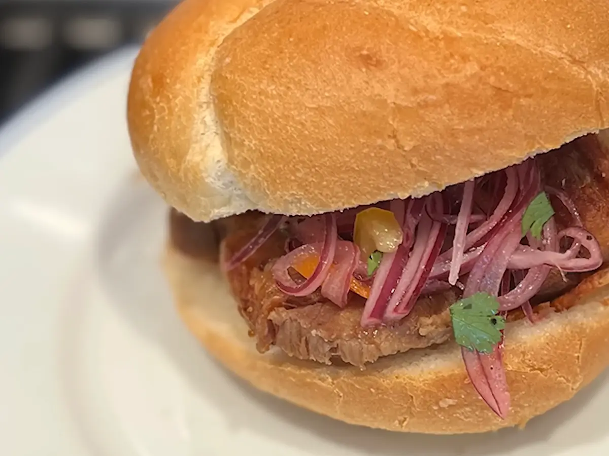 Panecillo relleno de cerdo asado con cebolla morada en escabeche, salsa criolla