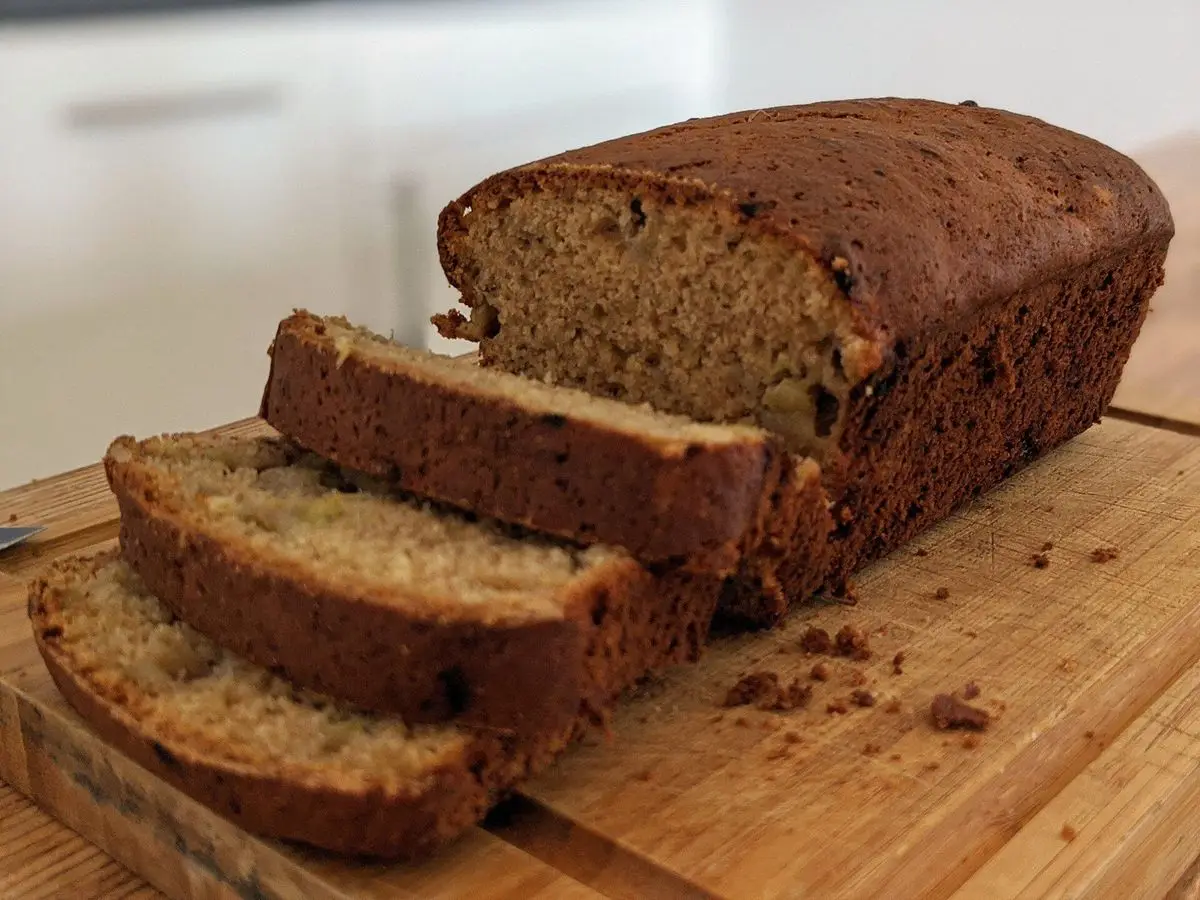 Pan de plátano dorado cortado en rebanadas sobre una tabla de madera