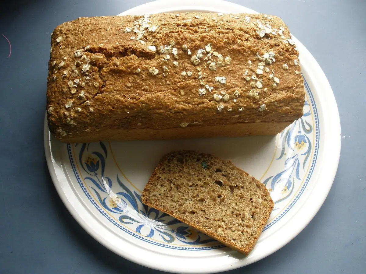 Hogaza de pan de soda integral con copos de avena y una rebanada sobre un plato